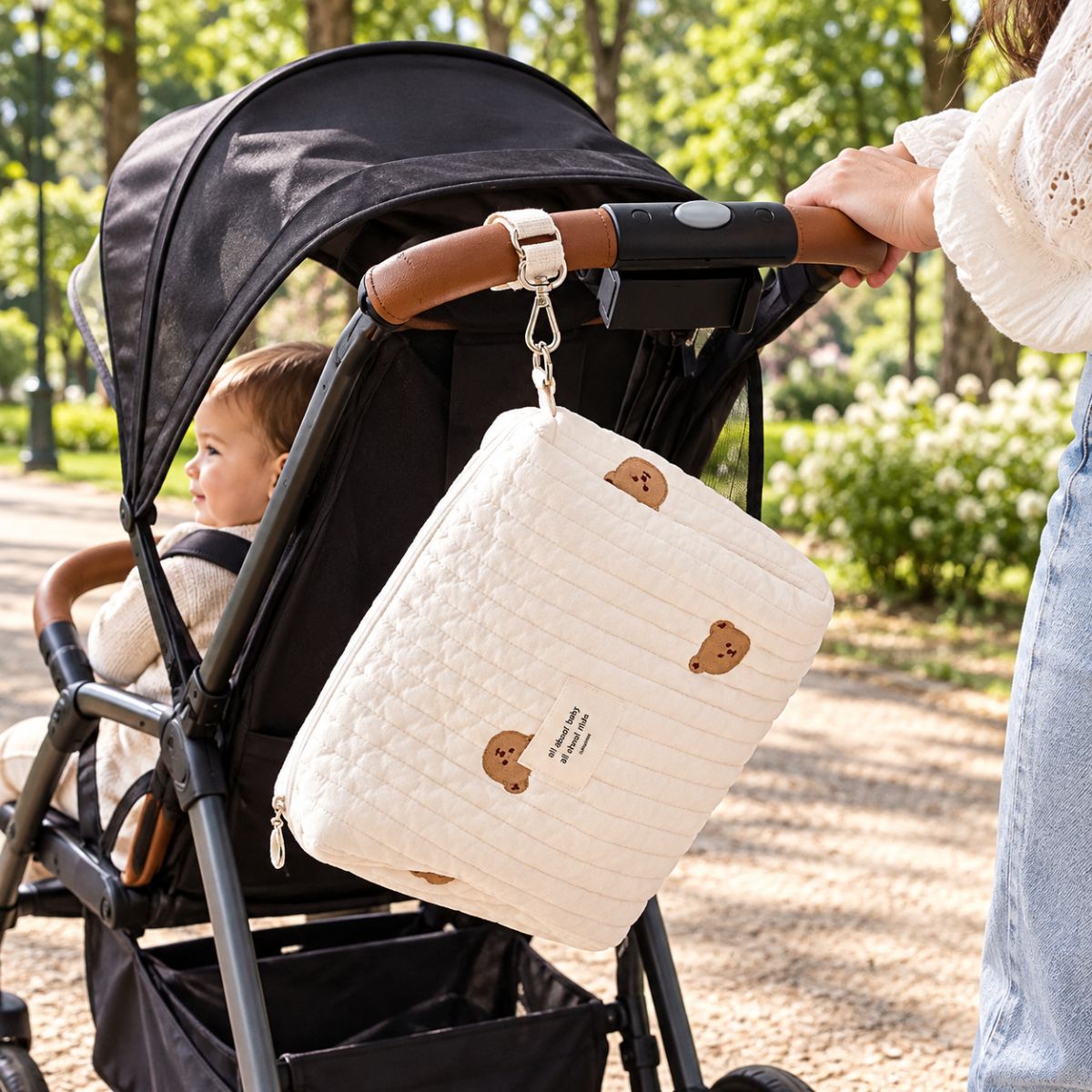 Sac à langer matelassé Petit Ourson suspendu à une poussette lors d’une sortie au parc