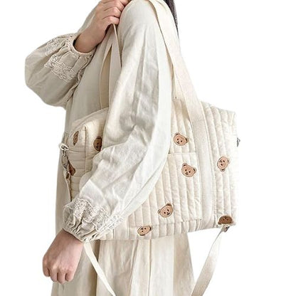 sac a langer crème au motif grand ourson, suspendu à l’épaule par une sangle réglable