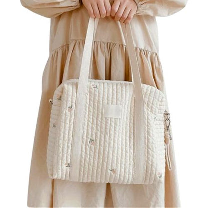 sac a langer matelassé avec feuillage tulipe fine, tenu devant une robe ample beige
