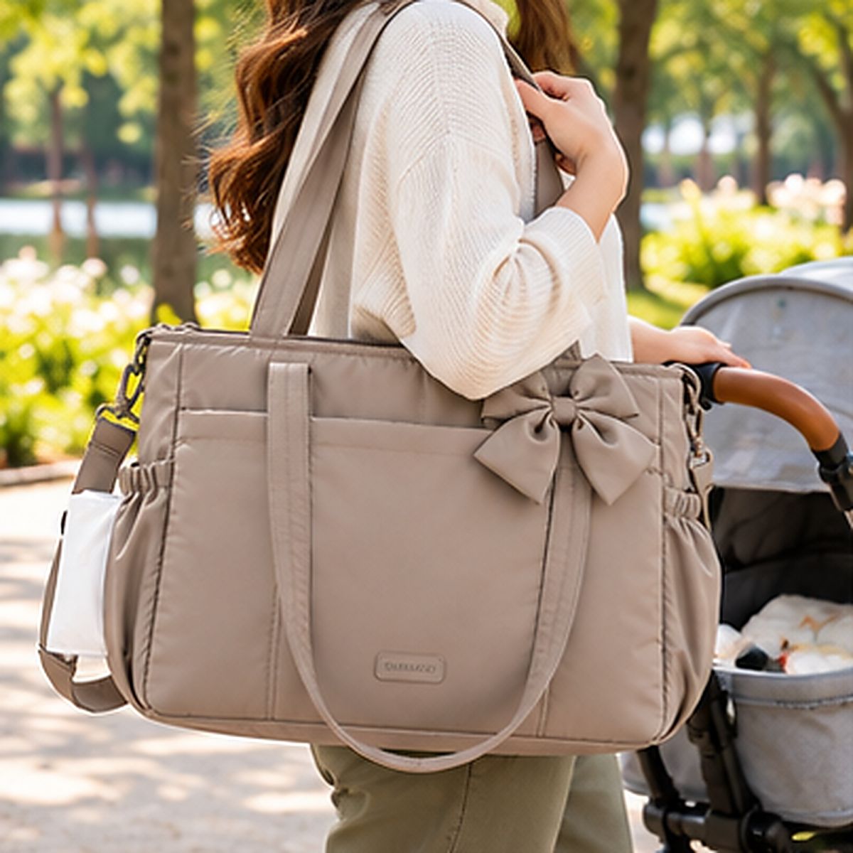 Sac à langer multifonction camel avec nœud assorti, deux anses et poches latérales, porté à l'épaule au parc