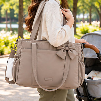 Sac à langer multifonction camel avec nœud assorti, deux anses et poches latérales, porté à l'épaule au parc