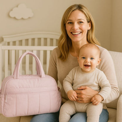 Sac a langer multifonction couleur rose à côté d’une maman souriante et de son bébé