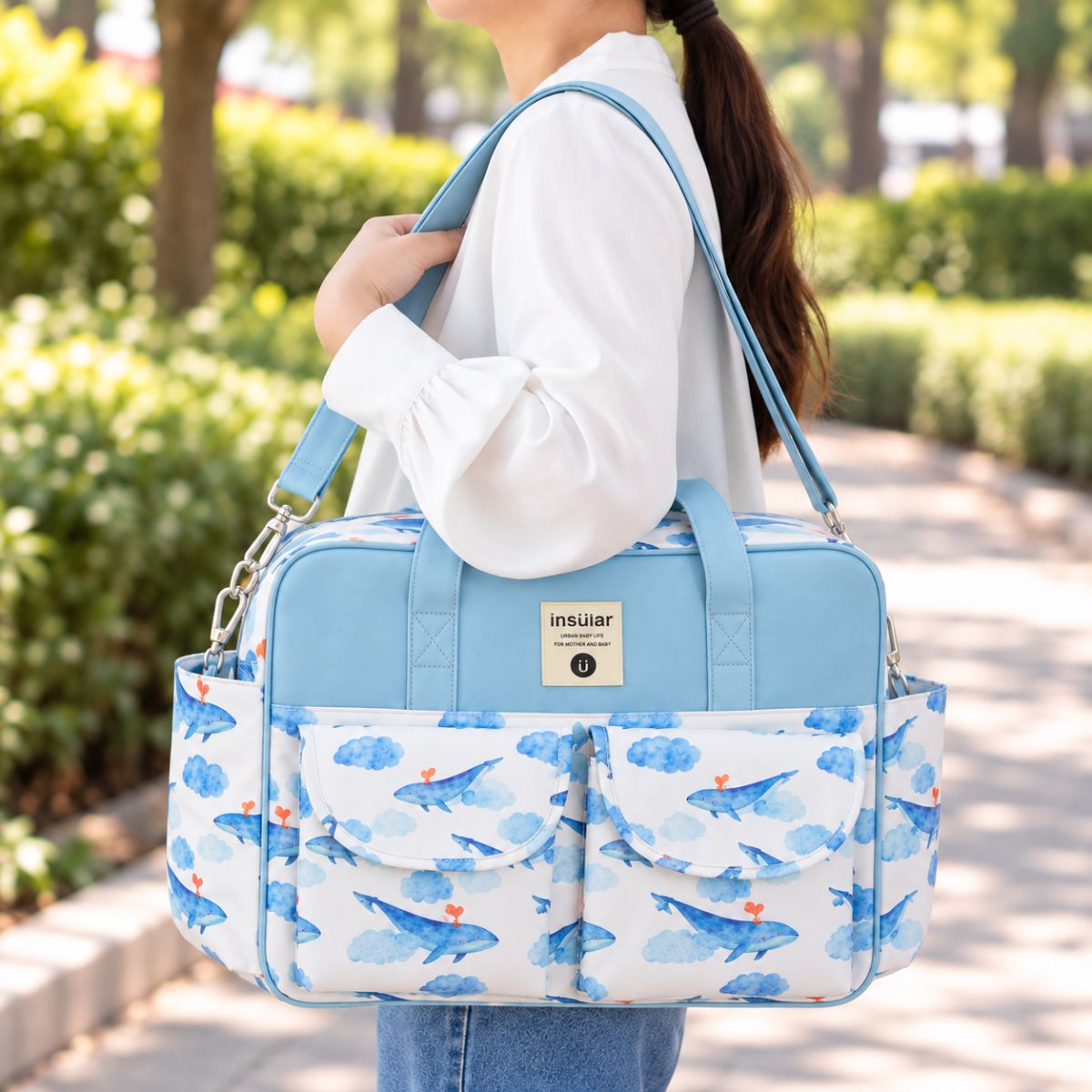 Sac à langer multipoches motif Baleine bleue porté à l’épaule en extérieur