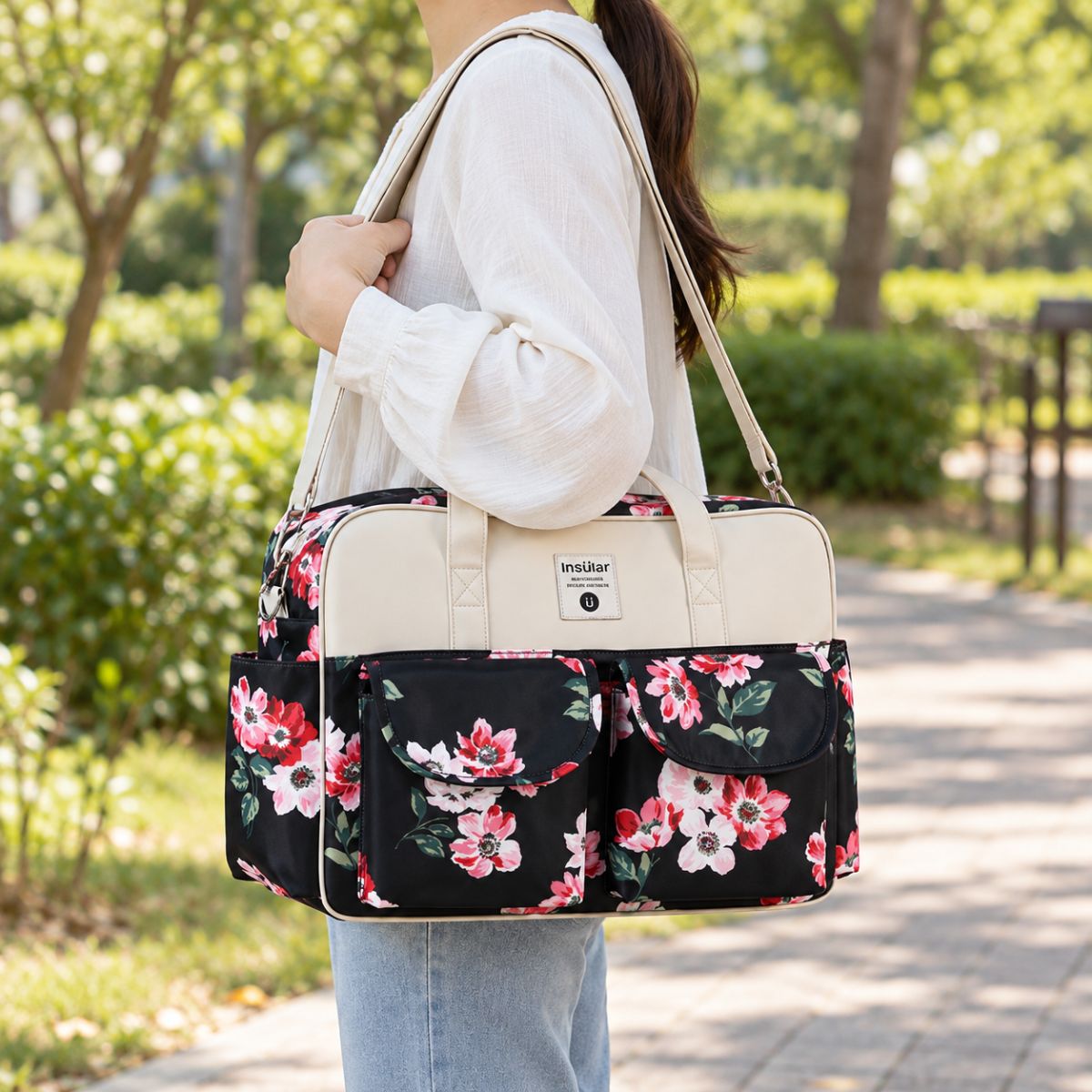 Sac à langer multipoches motif Floral noir et Blanc porté à l’épaule en extérieur