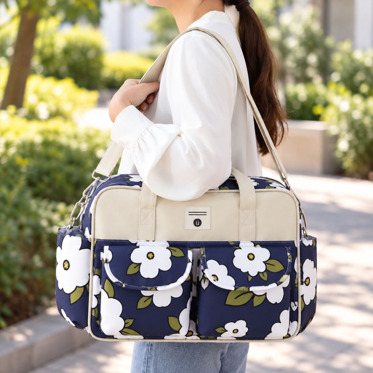 Sac à langer multipoches motif Iris d’Été bleu marine à fleurs blanches porté à l’épaule