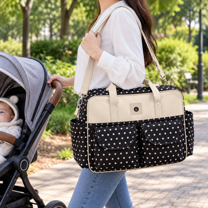 Sac à langer multipoches motif Pois noir et blanc porté à l’épaule près d’une poussette