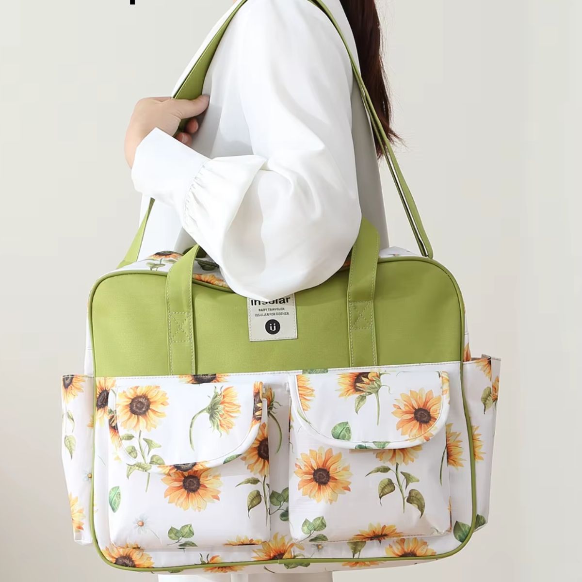Sac à langer multipoches motif Tournesol porté à l’épaule sur fond clair