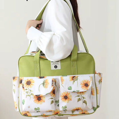 Sac à langer multipoches motif Tournesol porté à l’épaule sur fond clair
