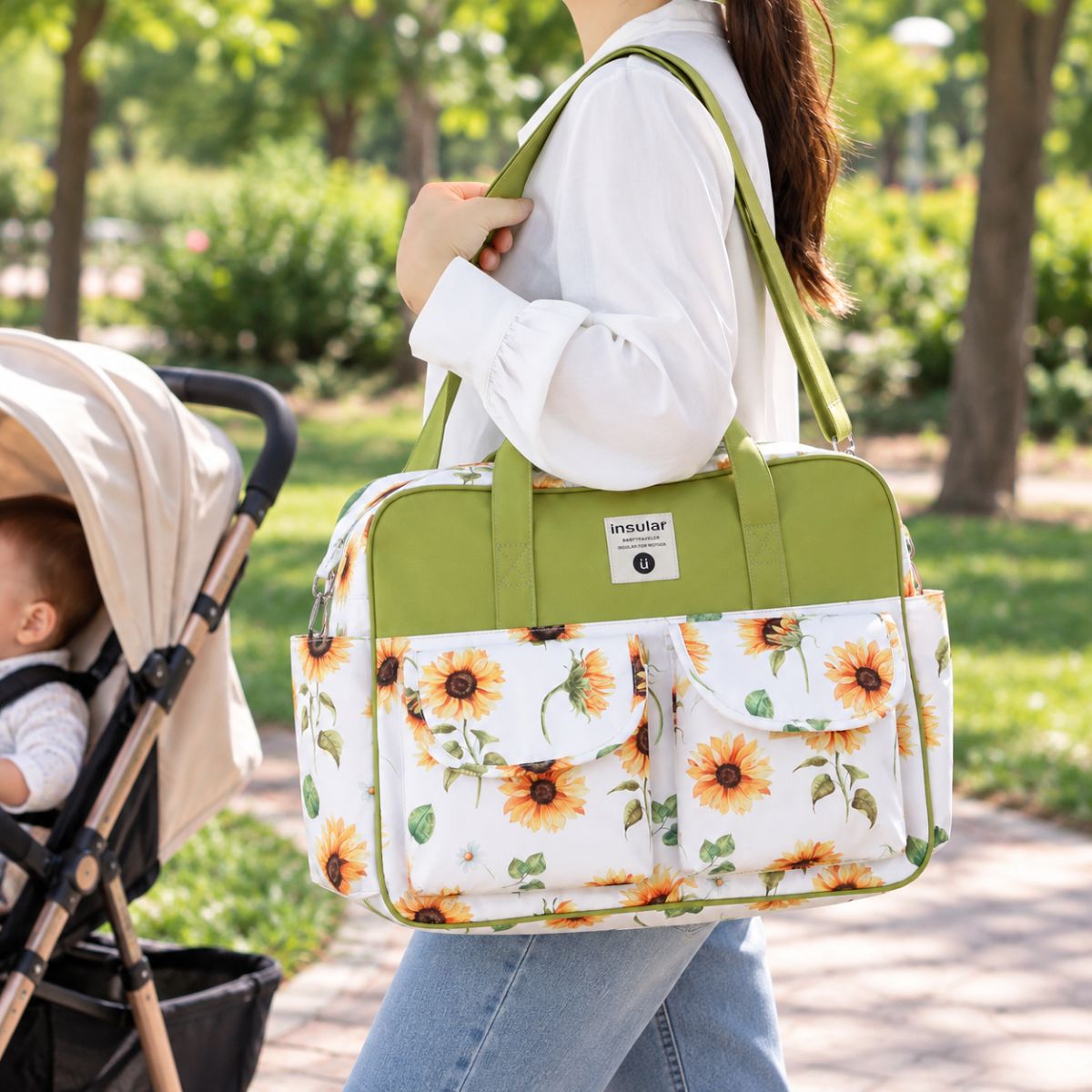 Sac à langer multipoches motif Tournesol porté à l’épaule près d’une poussette