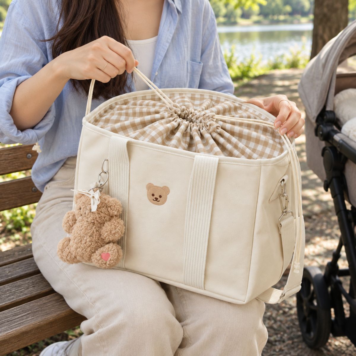 Sac à langer ourson  Beige avec doublure vichy et fermeture intérieure à cordon de serrage manipulée près d'une poussette