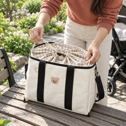 Sac à langer ourson finition Noir, posé sur une table en bois, avec ouverture à cordon et doublure intérieure vichy visibles