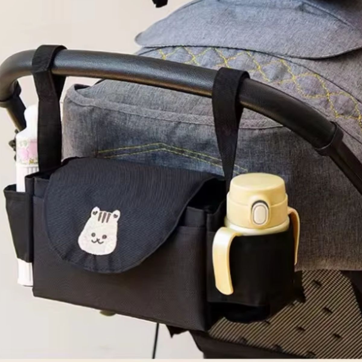 Sac a langer pour poussette motif écureuil noir accroché à une poussette grise