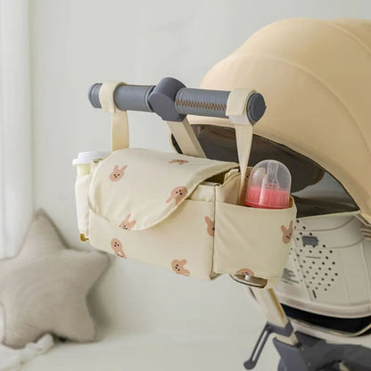Sac a langer pour poussette motif lapin beige fixé sur poussette avec biberon visible