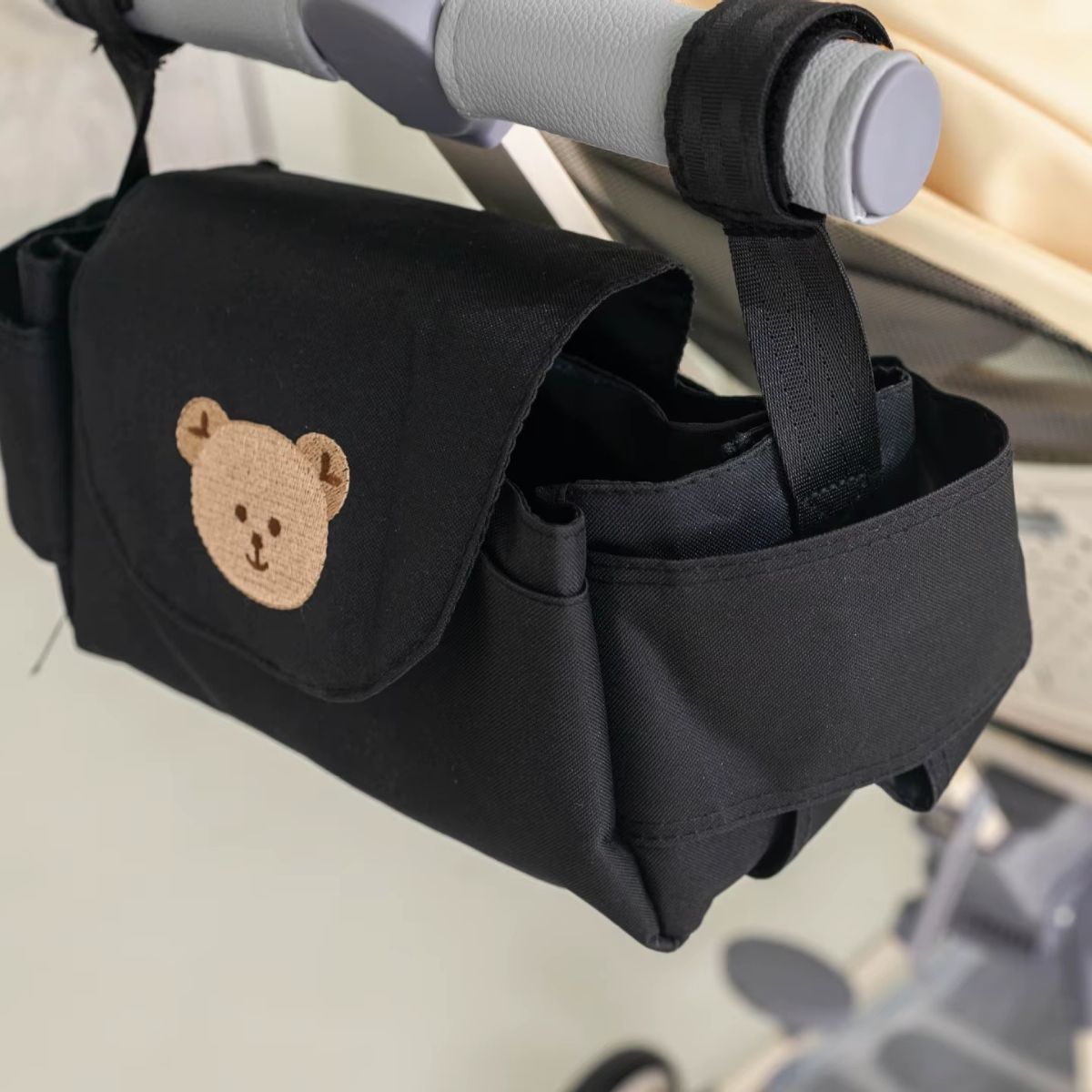 Sac a langer pour poussette motif ours beige fixé à une poussette claire