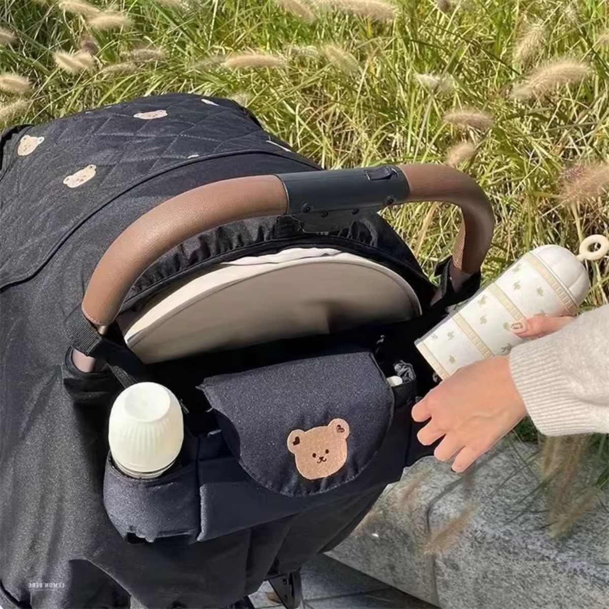Sac a langer pour poussette motif ours beige installé sur poussette noire en extérieur