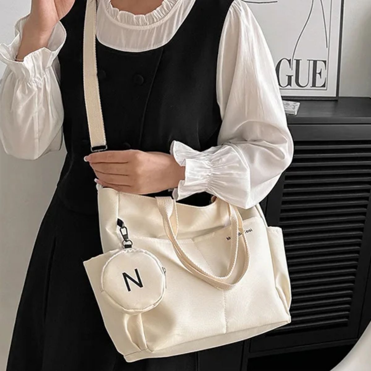 Sac a langer beige porté en bandoulière par une maman en haut noir et jupe claire