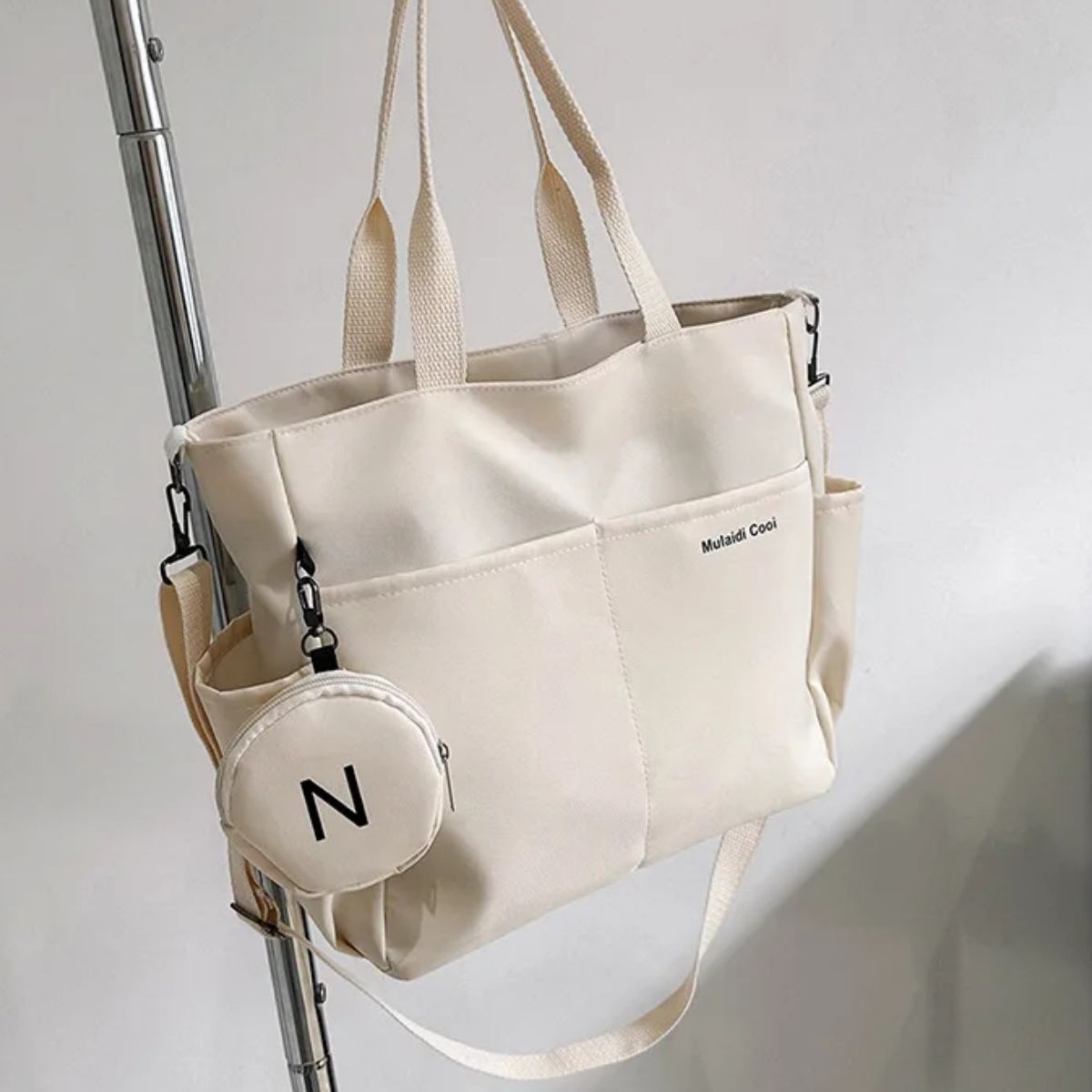 Sac a langer beige posé sur une chaise, vue de détail avec pochette ronde assortie