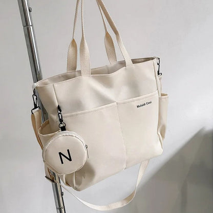 Sac a langer beige posé sur une chaise, vue de détail avec pochette ronde assortie