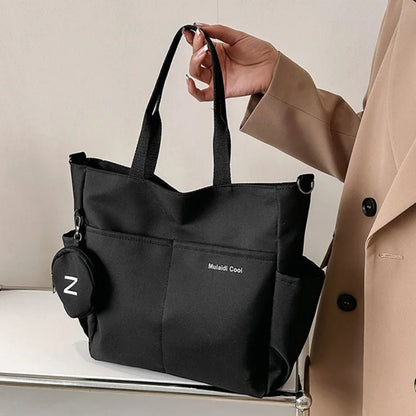 Sac a langer noir tenu à la main, design sobre posé sur une table blanche