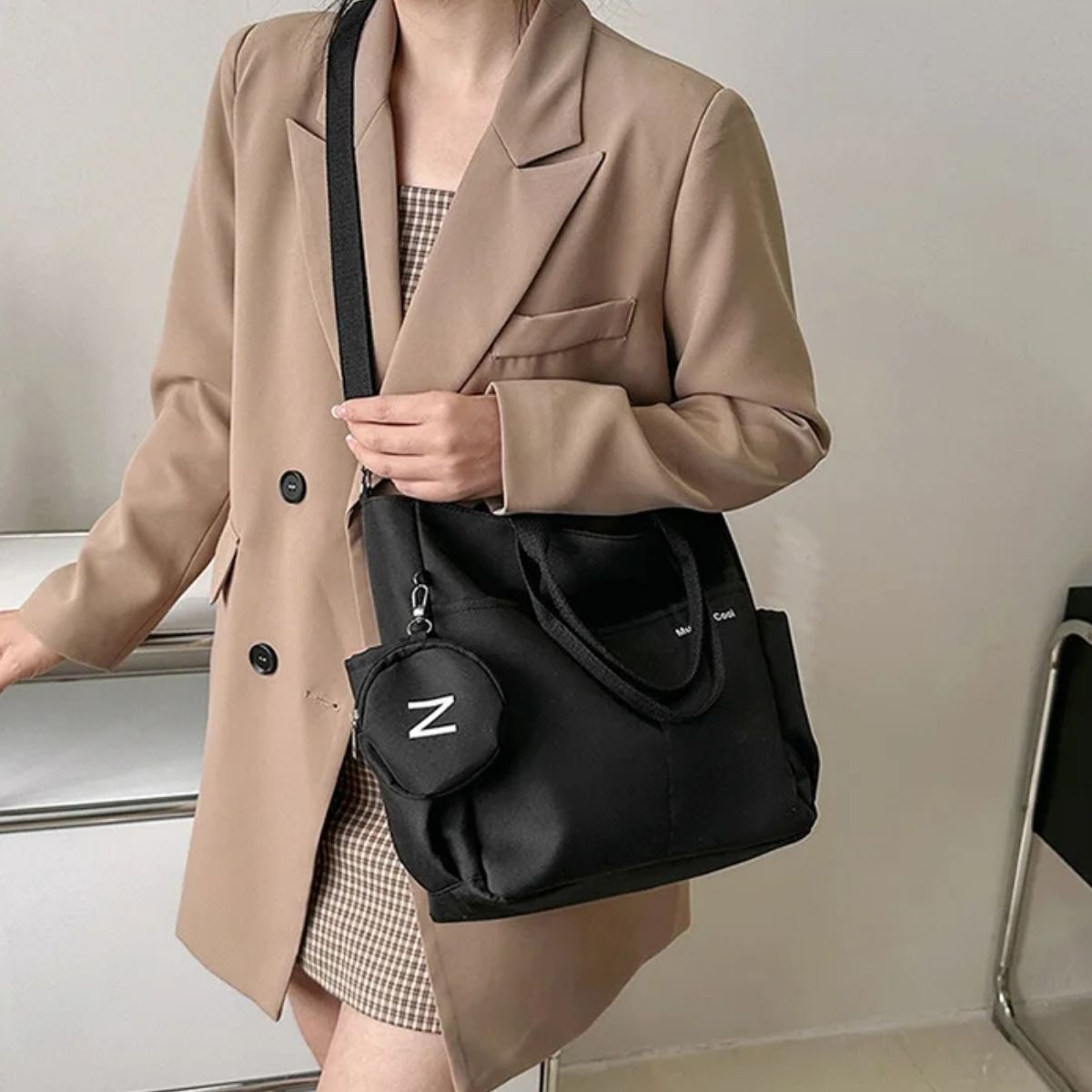 Sac a langer noir porté en bandoulière par une maman en tenue beige