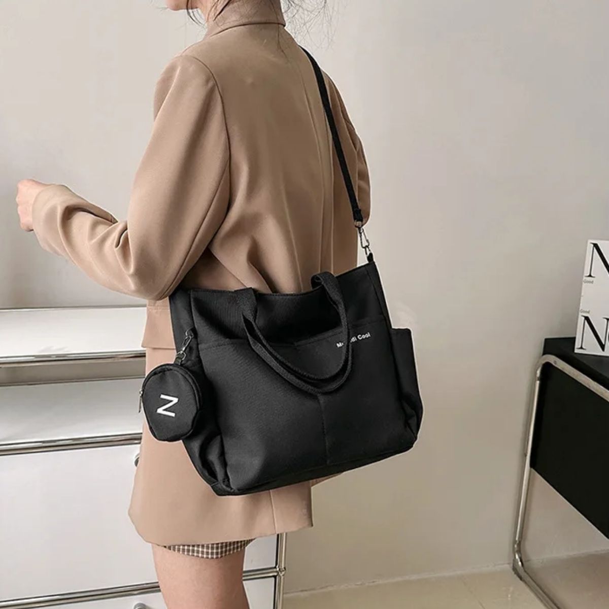 Sac a langer noir vu de dos, porté avec une sangle réglable par une maman debout