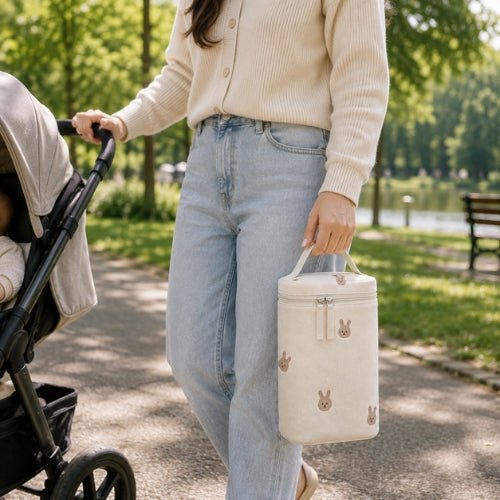 Sac à motifs pour biberon lapins porté par sa poignée intégrée lors d’une sortie avec bébé