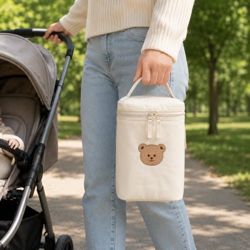 Sac à motifs pour biberon ours unique porté par sa poignée intégrée lors d’une sortie avec bébé