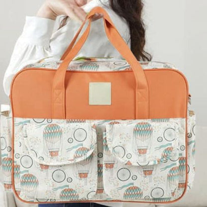 sac bebe montgolfiere porté à la main par une maman en chemise blanche