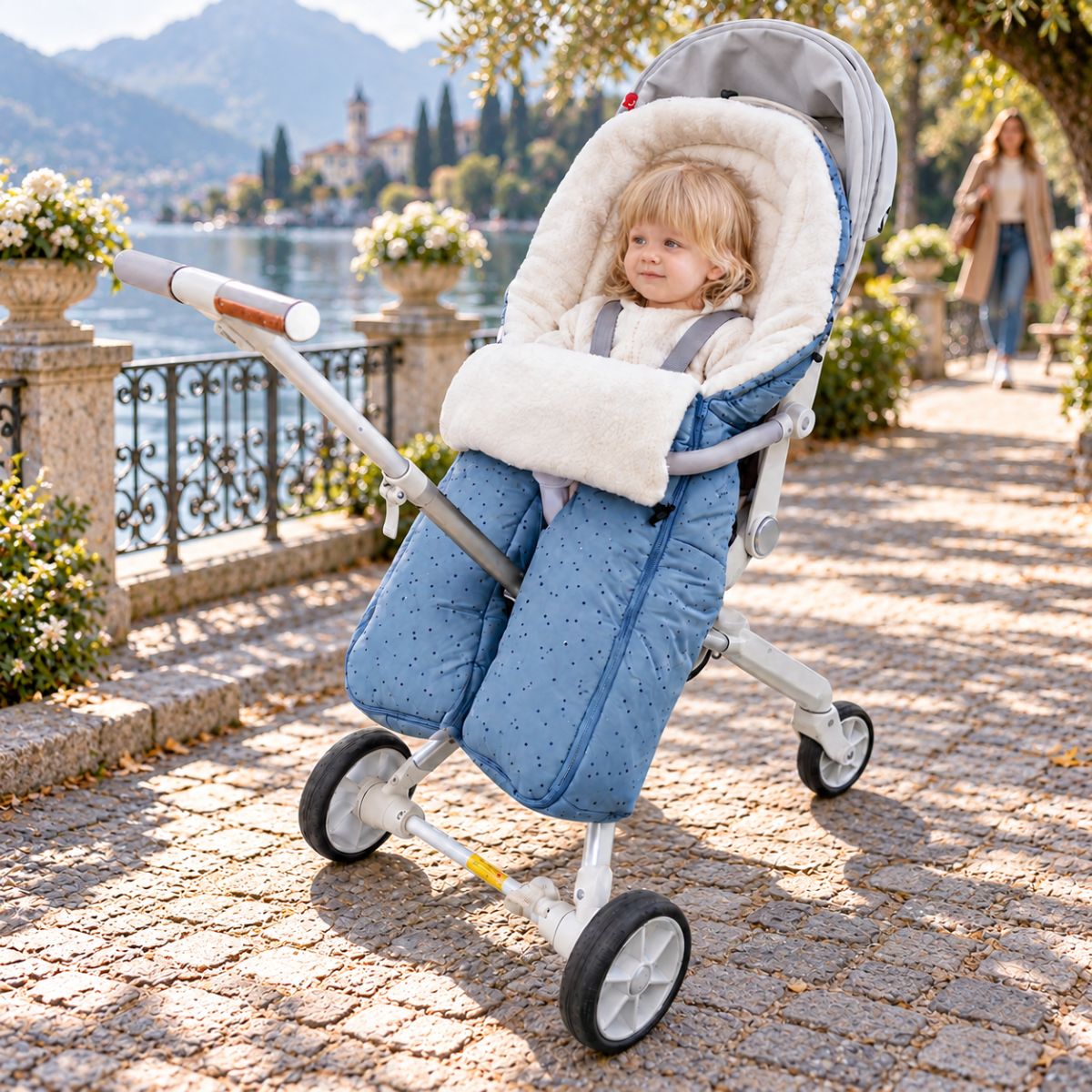 Sac de couchage pour poussette bleu clair à jambes séparées avec bébé lors d’une promenade près d’un lac