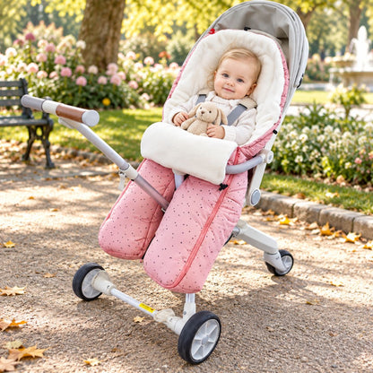 Sac de couchage pour poussette rose à jambes séparées avec intérieur blanc et bébé installé dans un parc fleuri