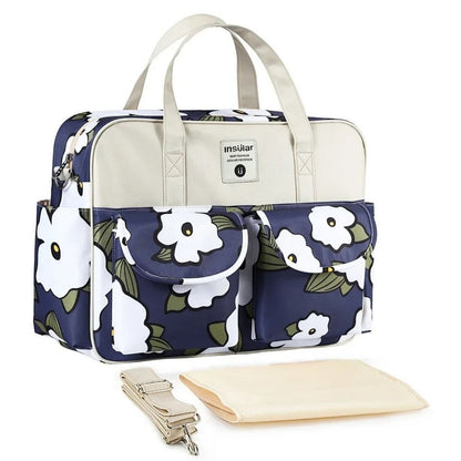 Sac de maternité Iris d’Été bleu marine avec fleurs blanches, vue produit posé avec sangle