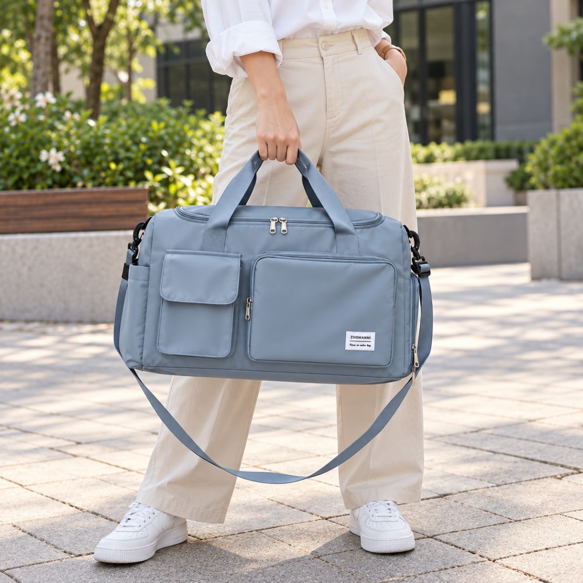 Sac de voyage avec compartiment chaussures bleu gris porté à la main