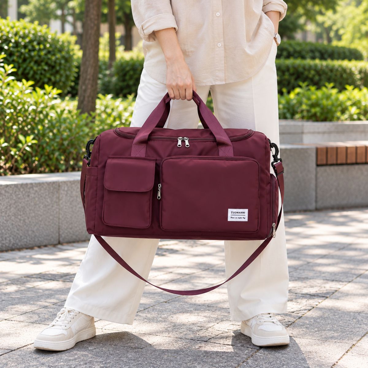 Sac de voyage avec compartiment chaussures bordeaux porté à la main