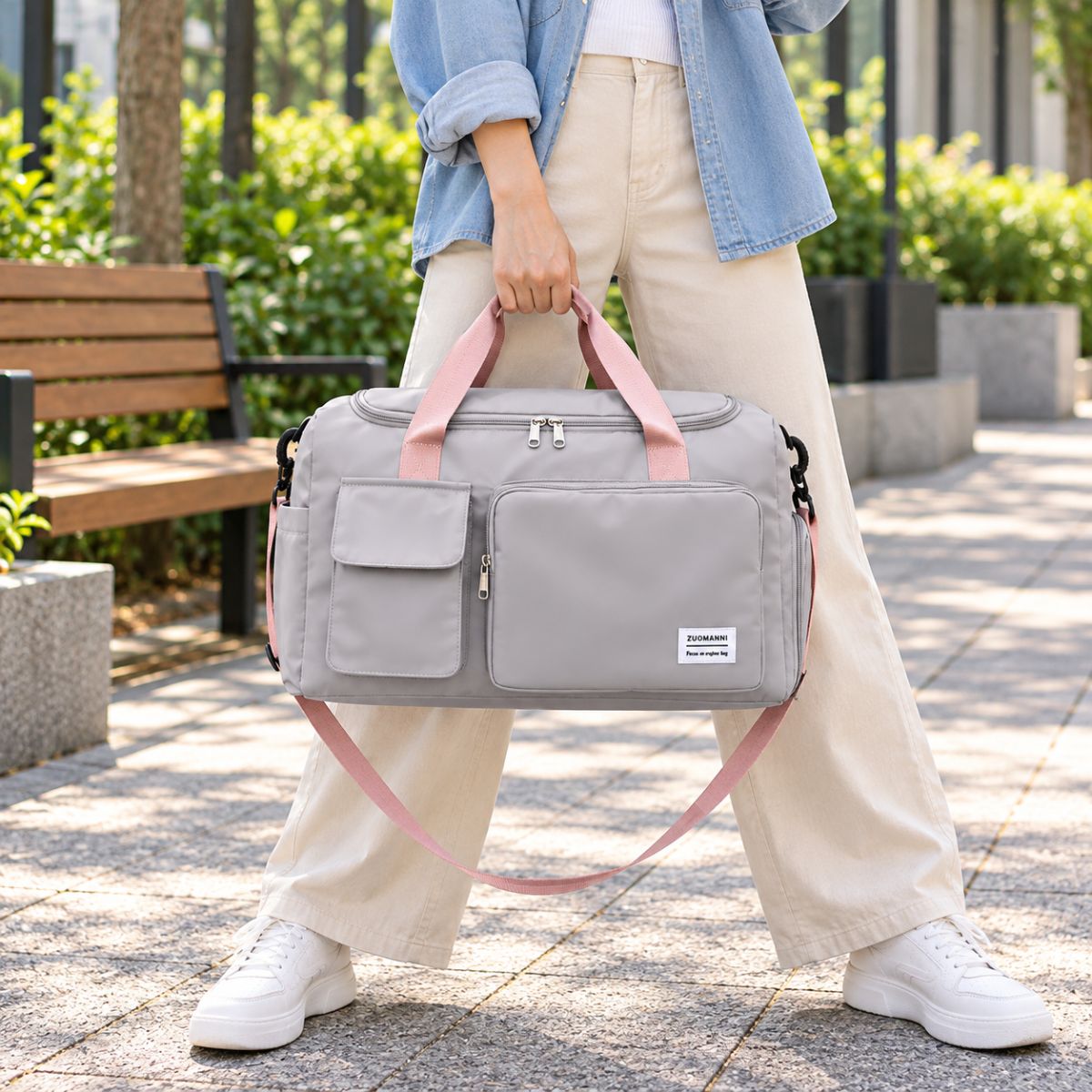 Sac de voyage avec compartiment chaussures gris perle porté à la main