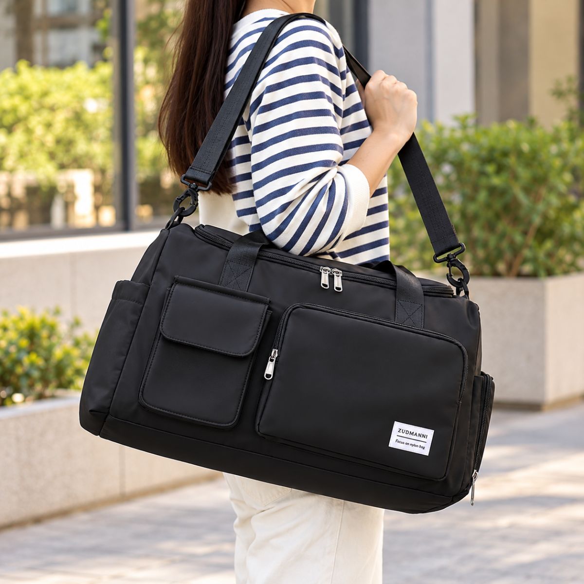 Sac de voyage avec compartiment chaussures noir porté à l’épaule