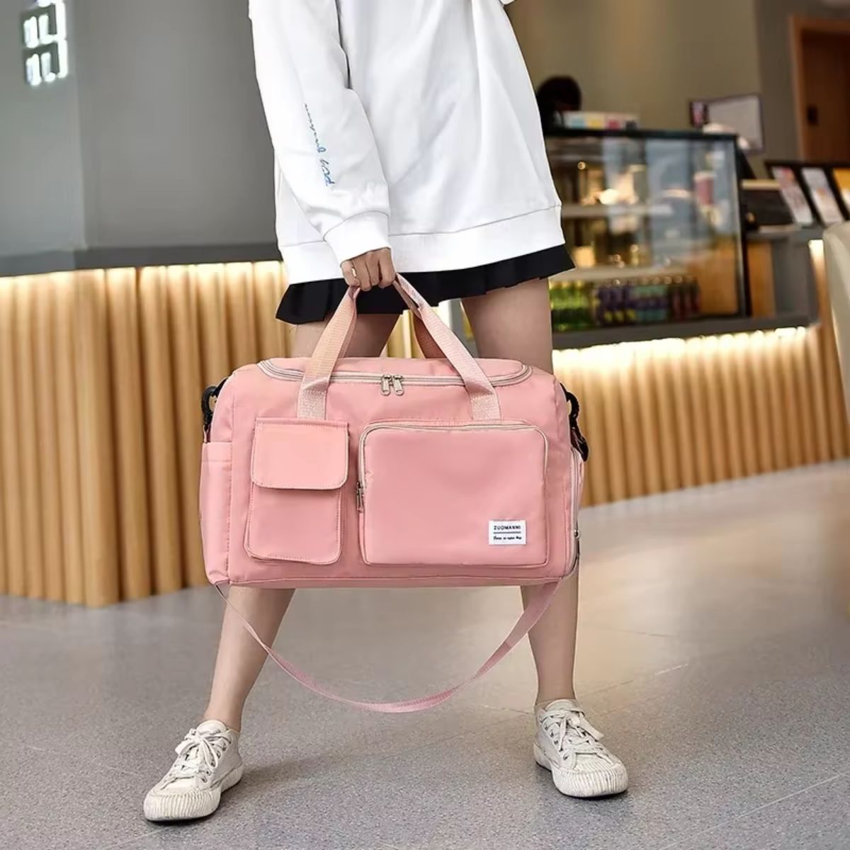 Sac de voyage avec compartiment chaussures rose saumon porté à la main