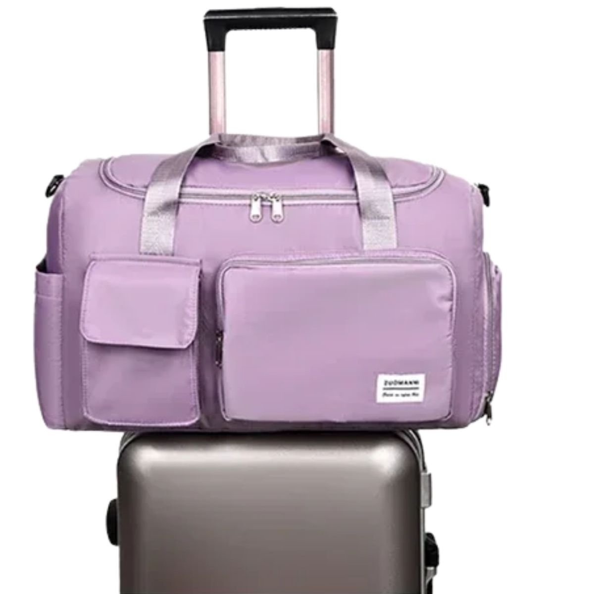 Sac maternité violet clair posé sur valise, poche avant visible