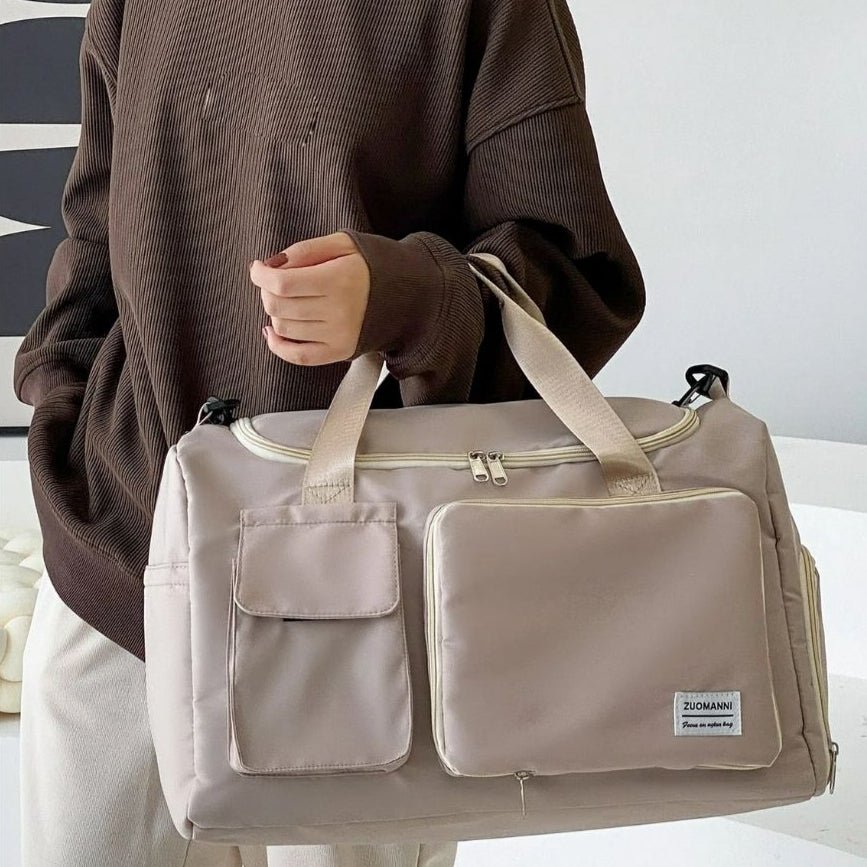 Sac maternité beige porté à la main par une femme en intérieur