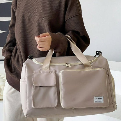 Sac maternité beige porté à la main par une femme en intérieur