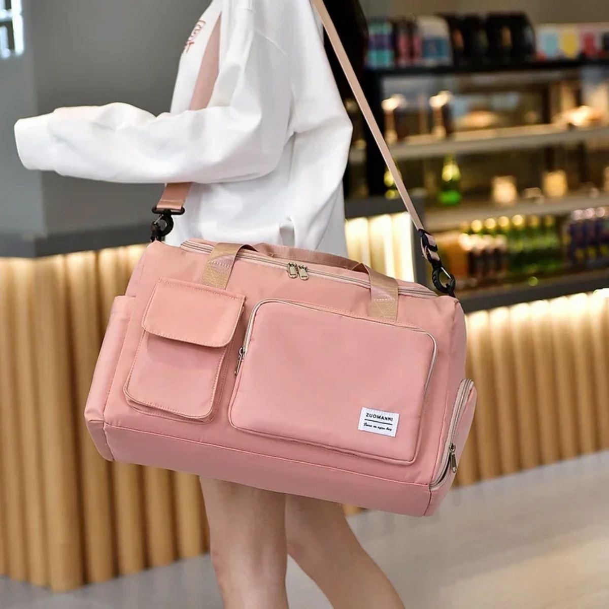 Sac maternité rose porté en bandoulière par une femme en intérieur