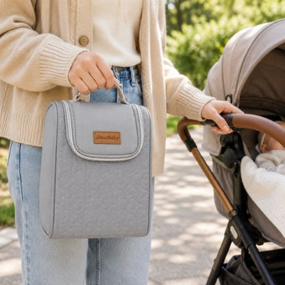 Sac pour deux biberons bleu avec poignée intégrée, porté à la main près d’une poussette