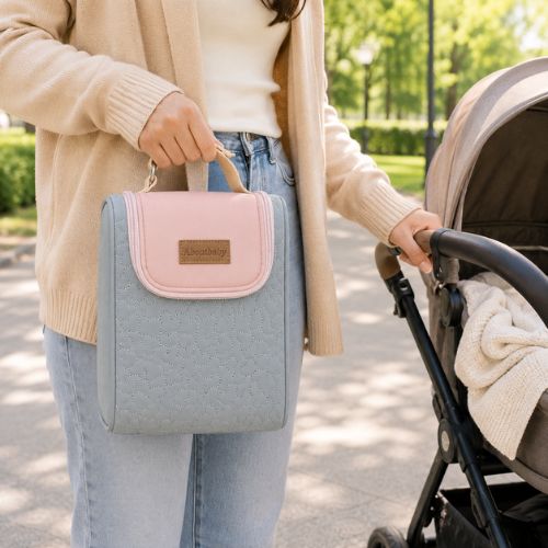 Sac pour deux biberons rose et gris avec poignée intégrée, porté à la main près d’une poussette