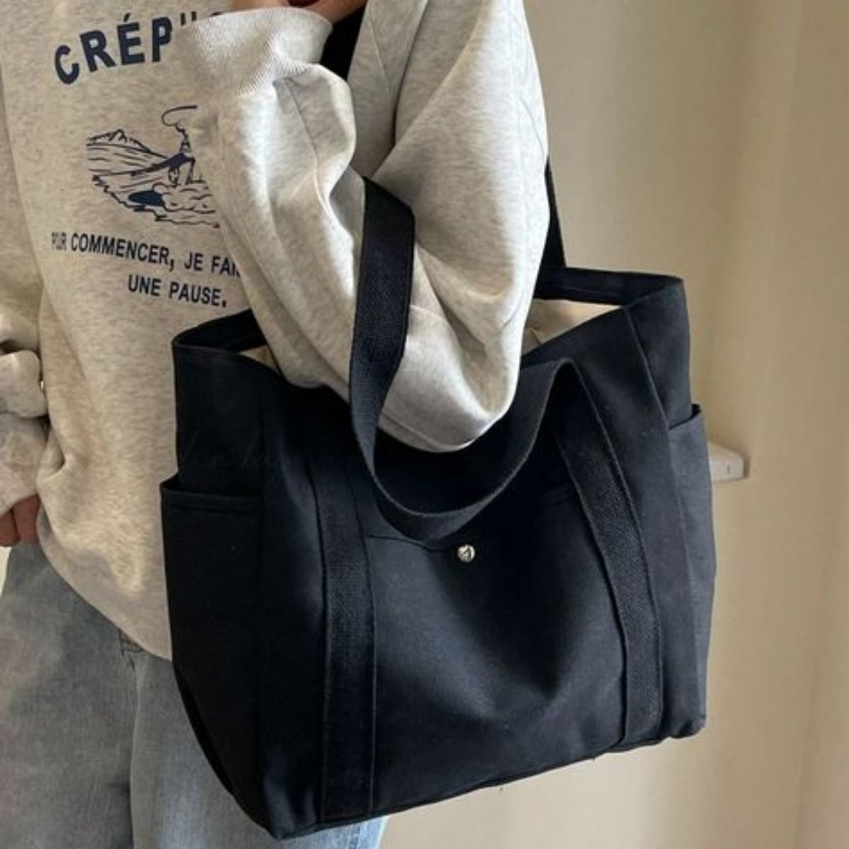 Sac pour la maternité noir porté à l’épaule, design sobre et pratique pour les sorties quotidiennes