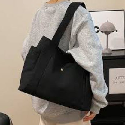 Sac pour la maternité noir vu de côté, porté à l’épaule, structure stable et résistante