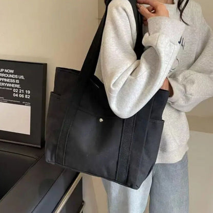 Sac pour la maternité noir porté à l’épaule, style discret et élégant adapté aux sorties