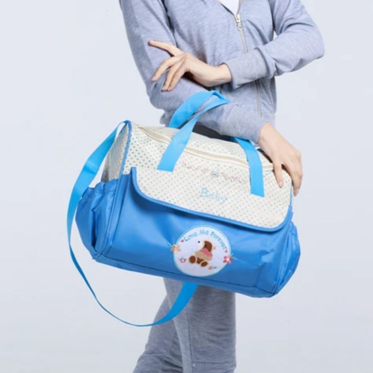 Sac pour la maternité bleu porté à la main par un parent, vue frontale