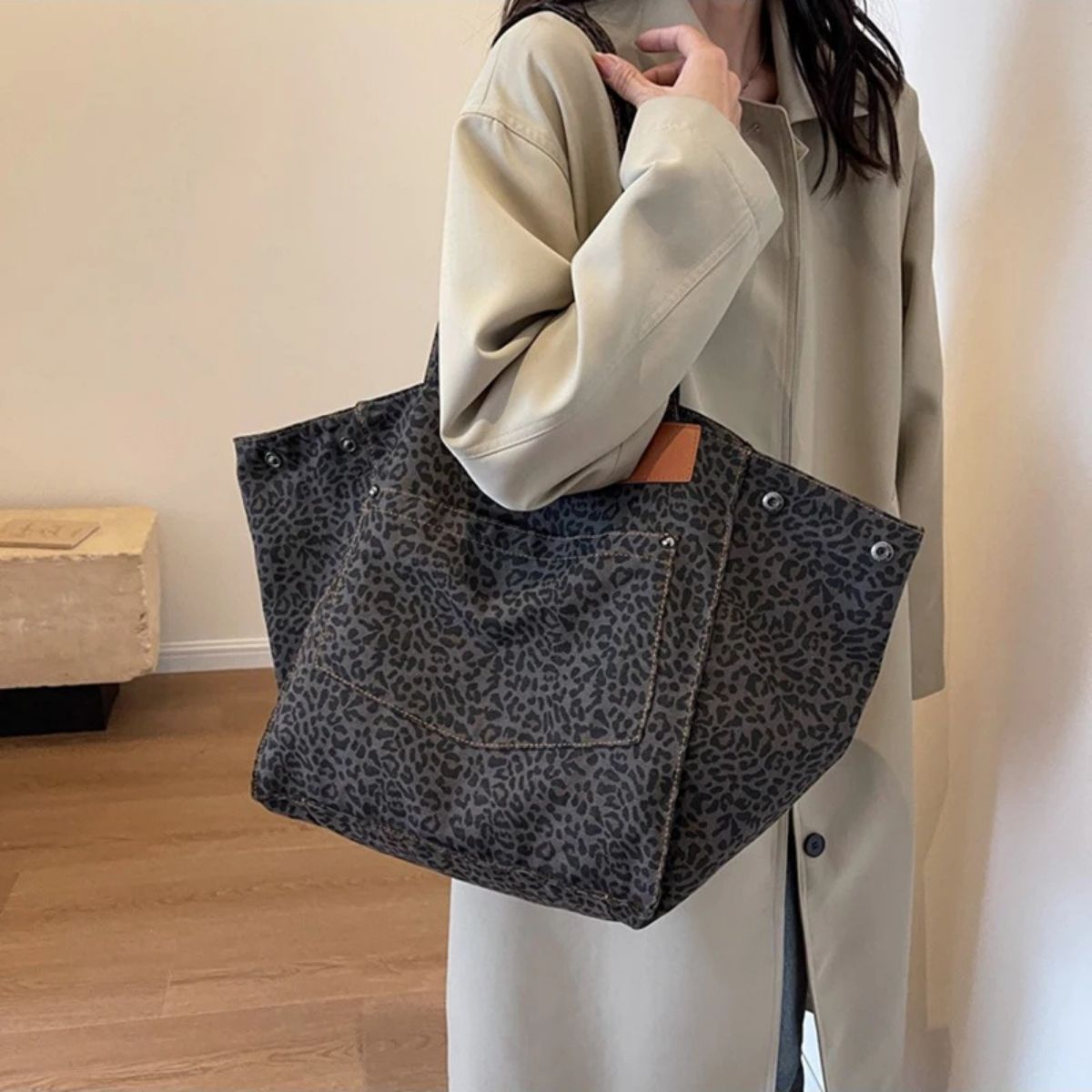 Sac pour la maternité léopard gris porté à l’épaule avec manteau beige, vue latérale