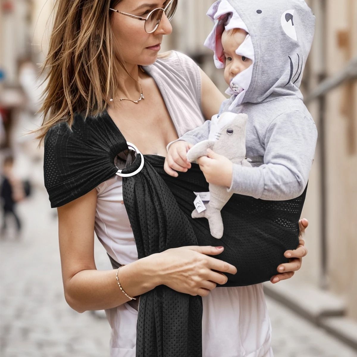 Sling echarpe de portage noir utilisé en ville par maman avec bébé